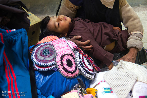 کودک خوابیده در آغوش مادر (دستفروش) در بازار زابل