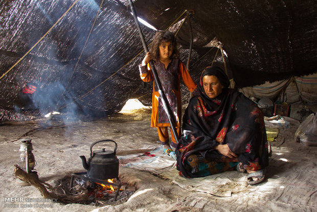 یک زن و فرزند در چادر سیاه عشایری و تهیه چای روزانه در منطقه تالاب هامون استان سیستان و بلوچستان