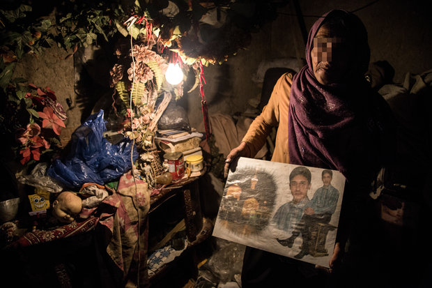 زن 50 ساله ساکن شهر زابل عکس پسر سالمش را که چند سالیست که او را ندیده است به دوربین نشان میدهد
