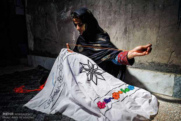 گلنار برای رو بالشی جهیزیه خود سوزن می زند، سوزن دوزی یکی از صنایع دستی مردم سیستان است.