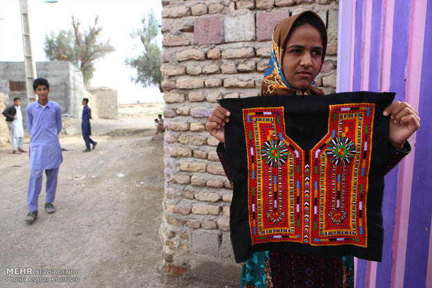دختر زابلی پیراهن سوزن دوزی شده که از صنایع بسیار زیبای این شهر محسوب می شود را نمایش می دهد