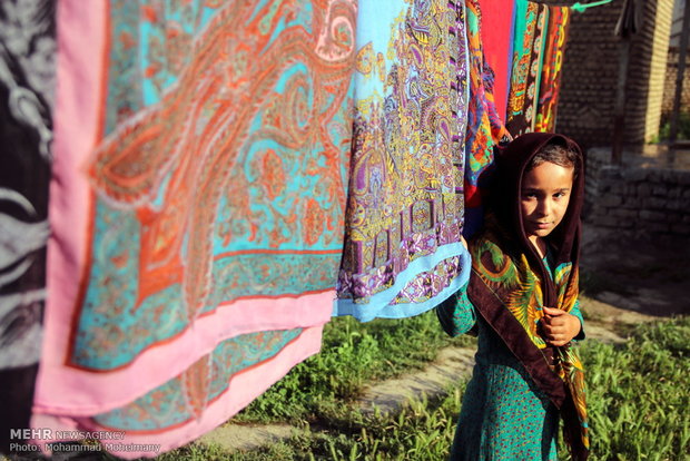 دختر ترکمن در کنار روسری های سنتی ترکمنی
