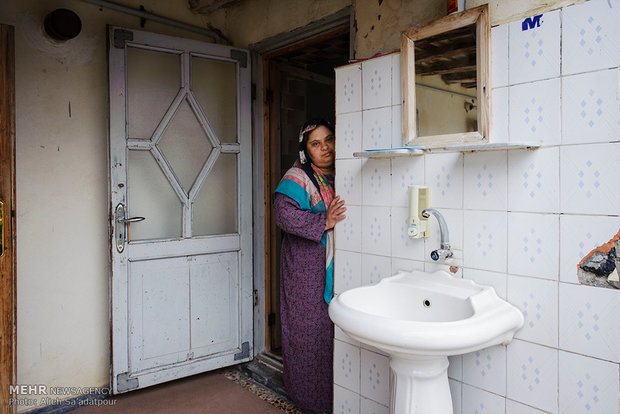 دختر ترکمن مبتلا به سندروم داون در ورودی خانه خود ایستاده است.