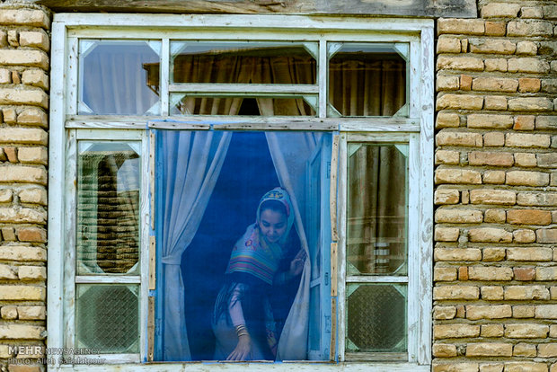 صدیقه رجب زاده، 22 ساله پشت پنجره یکی از منازل قدیمی گمش تپه دیده می شود.