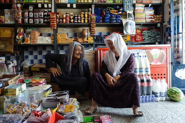 دو زن مسن ترکمن در مغازه مواد غذایی خود در شهر گمش تپه مشغول گفتگو هستند. اغلب زنان ترکمن در بیرون منزل مشغول به کار هستند و مغازه دارند.