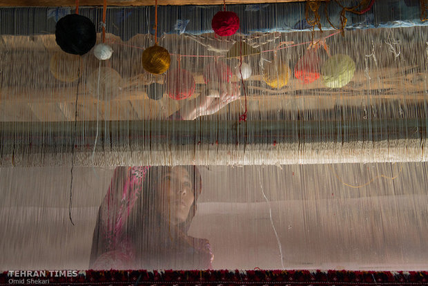 A Turkmen weaver sits by her loom working on weaving a colorful carpet. Taklah Quz women set up carpet looms during cold season. The village is known for its astonishing double-sided carpets. 