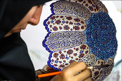 A craftswoman meticulously brush paints a traditional fruit pot in an undated photo.