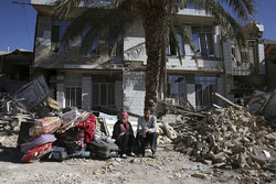 Survivors sit in front of a destroyed house on the earthquake site in Sarpol-e Zahab in western Iran. (AP/Vahid Salemi)