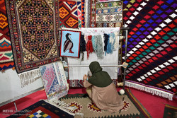 A woman seating apposite a carpet loom practices weaving a rug during her visit to a national handicrafts sales exhibit in Shiraz, southern Iran, February 27, 2018.