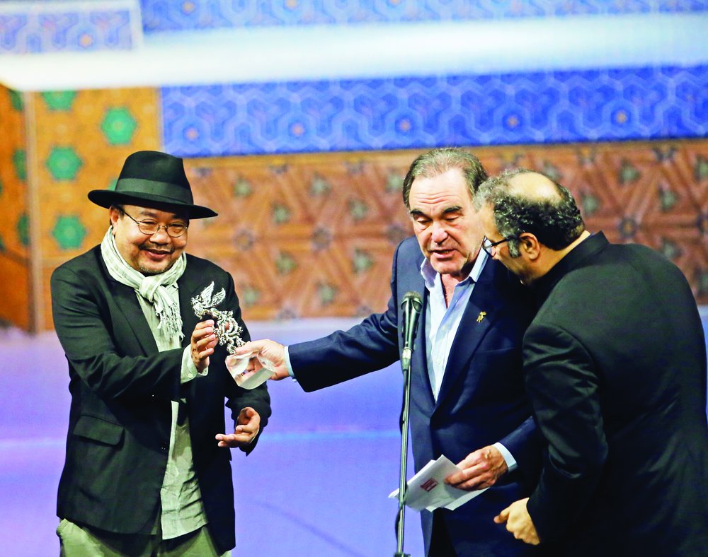 Cambodian filmmaker Rithy Panh (L) receives the Peace Prize from American director Oliver Stone during the closing ceremony of the Fajr International Film Festival at Tehran’s Vahdat Hall on April 26,