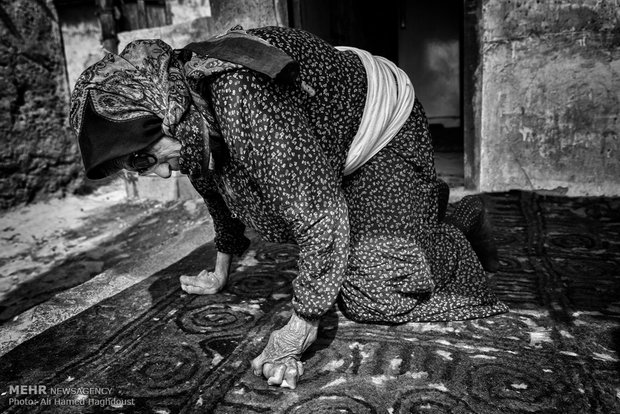 جمعه گل نوری 71 ساله در حال حرکت در بیرون اتاق خانه خود است. او در اتاقی در گوشه حیاط یکی از روستائیان زندگی می‌کند. دست و پاهای او در اثر سوختن در تنور در ایام کودکی دچار معلولیت شدید شد.