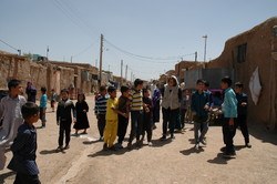 Negar Gerami, wearing head scarf, is talking to a group of Afghan national children in a refugee settlement in Saveh, Markazi province. 