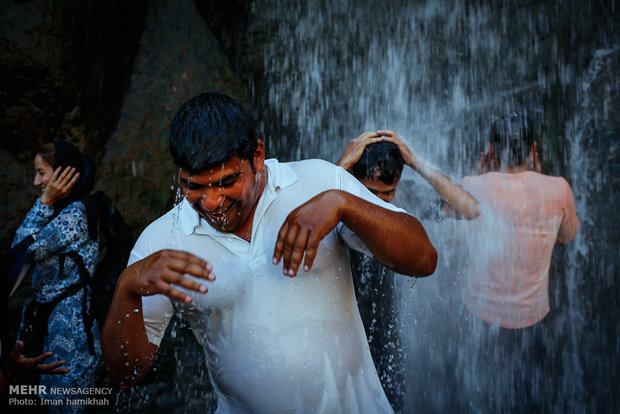 Tourists escaping from hot weather at Ganjnameh waterfall