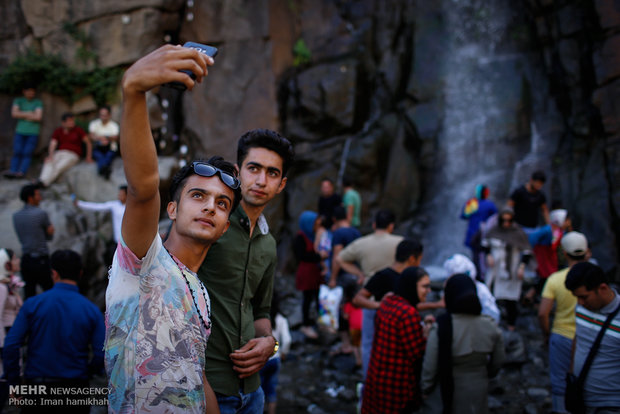 Tourists escaping from hot weather at Ganjnameh waterfall