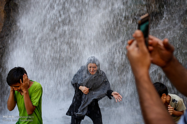 Tourists escaping from hot weather at Ganjnameh waterfall