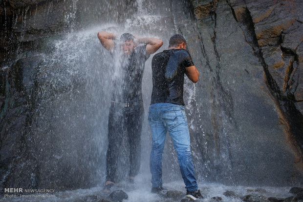 Tourists escaping from hot weather at Ganjnameh waterfall