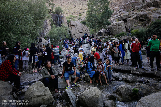 Tourists escaping from hot weather at Ganjnameh waterfall