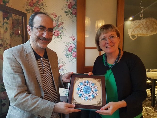 This undated photo shows Book City Institute deputy director Ali-Asghar Mohammadkhani (L) and Imants Ziedonis Foundation director Žaneta Jaunzeme-Grende posing with an Iranian artwork presented to the