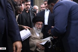 Leader of the Islamic Revolution Ayatollah Seyyed Ali Khamenei takes a glance at a book he received during a meeting with literati and filmmakers on September 16, 2019. (Khamenei.ir)