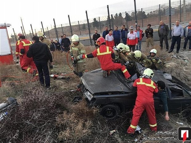 آتش‌نشانان دو سرنشین خودروی پژو 405 متلاشی شده را که پس از واژگونی هر...