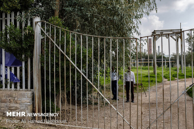 نگهبانان پشت درهای بسته قدیمی ترین پالایشگاه خاورمیانه (بی بیان) در شهر مسجد سلیمان ایستاده اند.