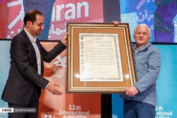 Iranian film scholar Akbar Alami (R) poses with IIDCYA director Fazel Nazari after being honored for his lifetime achievements during the 11th Tehran International Animation Festival on March 7, 2019.