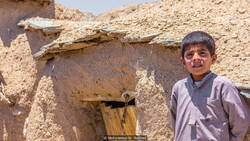 A boy stands by a tiny house in Makhunik, eastern Iran.  