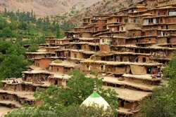 A view of the touristic village of Masuleh in Gilan province. It features earth-colored houses that are stacked photogenically on top of one another like giant Lego blocks, clinging to a mountainside so steep that the roof of one house forms the pathway for the next.