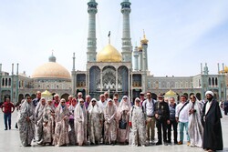 International travelers pose for a photo while visiting the holy shrine of Hazrat Masumeh (SA), the sister of Imam Reza (AS), in Qom, central Iran. Women are clad in chadors, shapeless gowns that cover their entire bodies, to respect a dress code required for female pilgrims.