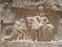 A bas-relief carving at Naqsh-e Rostam depicts Shapur I (on horseback) capturing Roman emperor Valerian (standing) and Philip the Arab (kneeling), suing for peace, following the victory at Edessa