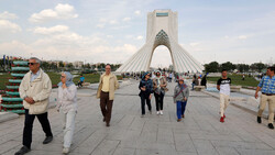 File photo: People walk pass the Azadi Tower, western Tehran. The inverted-Y-shaped monument is one of visual icons of the Iranian capital.
