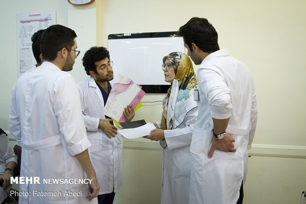 دکتر گرانپایه در درمانگاه بیمارستان، به شاگردان علوم پزشکی، نکاتی را در جهت معاینه بیماران، آموزش می دهد