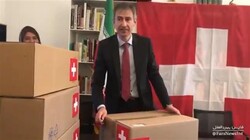 Frame grab from a video published by Fars News Agency shows Swiss Ambassador to Tehran Markus Leitner’s posing with medicine cartons inscribed with the Swiss flag after their transfer into the country.