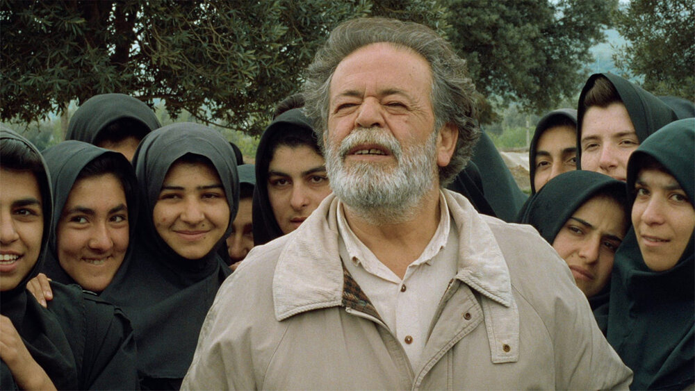 Mohammad-Ali Keshavarz and schoolgirls from Koker act in a scene from “Through the Olive Trees”, one of Abbas Kiarostami’s movies from The Koker Trilogy.