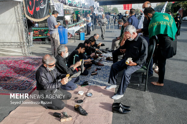 تعدادی از خادمان با تمیز کردن کفش شرکت کنندگان مراسم راهپیمایی جاماندگان اربعین حسینی(ع) در برنامه حضور پیدا کردند
