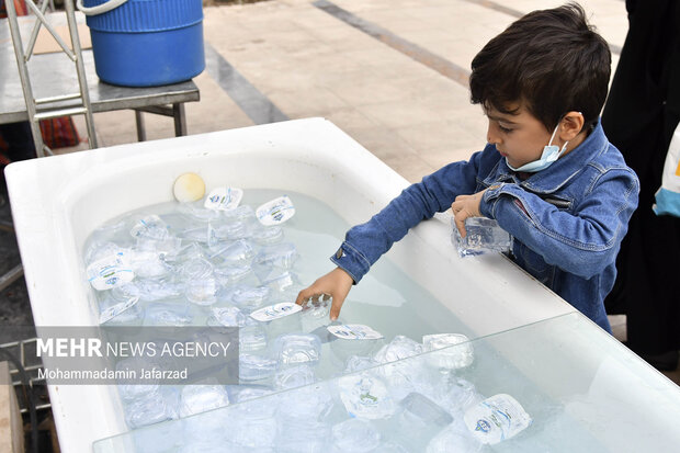 یک کودک در حال برداشتن آب های تک نفره یادبود مسیر راهپیمایی اربعین حسینی است 