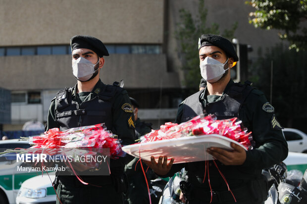 ماموران نیروی انتظامی به مناسبت هفته نیروی انتظامی برای اهدای گل به شهروندان تهرانی در میدان ولیعصر حضور دارند