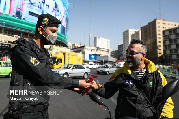 یکی از ماموران نیروی انتظامی به مناسبت هفته نیروی انتظامی  به شهروندان تهرانی در میدان ولیعصر گل اهدا میکند