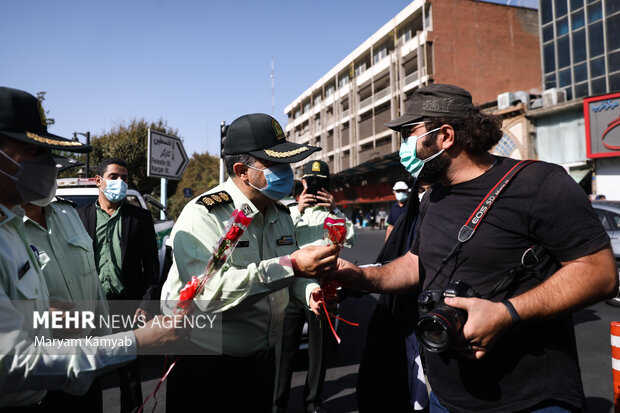یکی از ماموران نیروی انتظامی به مناسبت هفته نیروی انتظامی به احمد بلباسی عکاس خبرگزاری صدا وسیما گل اهدا می کند 