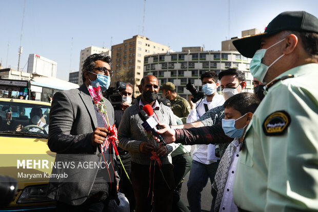 یکی از ماموران نیروی انتظامی به مناسبت هفته نیروی انتظامی  به شهروندان تهرانی در میدان ولیعصر گل اهدا میکند