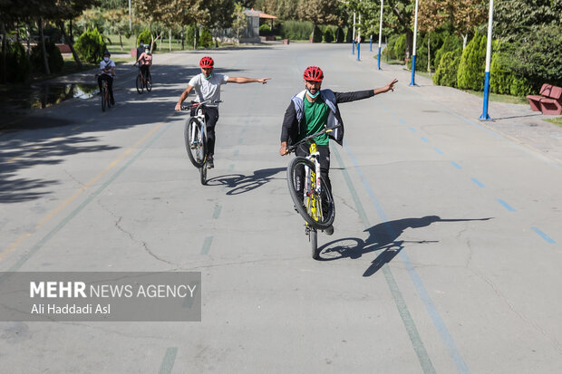 دو دوچرخه سوار در طول مسیر مسابقه همیاران پلیس به اجرای حرکات نمایشی می پردازند