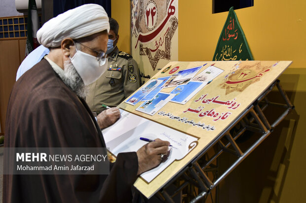 حجت الاسلام محمد حسنی رئیس سازمان عقیدتی سیاسی ارتش جمهوری اسلامی ایران در حال نوشتن یادگاری در مراسم رونمایی از آثار جدید فرهنگی است 