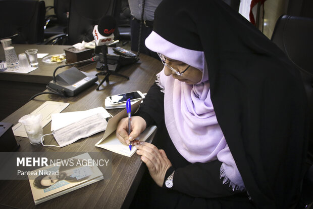 آزاده جهان احمدی نویسنده کتاب های  زندگی نامه داستانی قاضی طباطبایی و آیت الله بروجردی در حال امضای کتاب ها برای اهدا به حضار در جلسه رونمایی کتاب است