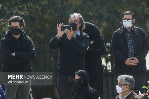 صیف الله صمدیان در حال تصویربرداری با دوربین تلفن همراه از مراسم تشییع پیکر مرحومه ایران درودی هنرمند نقاش است