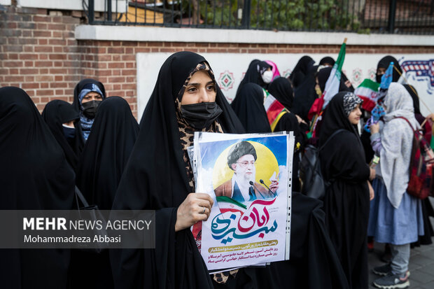 یکی از خانم های حاضر در مراسم یوم الله ۱۳ آبان در مقابل لانه جاسوسی امریکا  عکس مقام معظم رهبری را در دست دارد