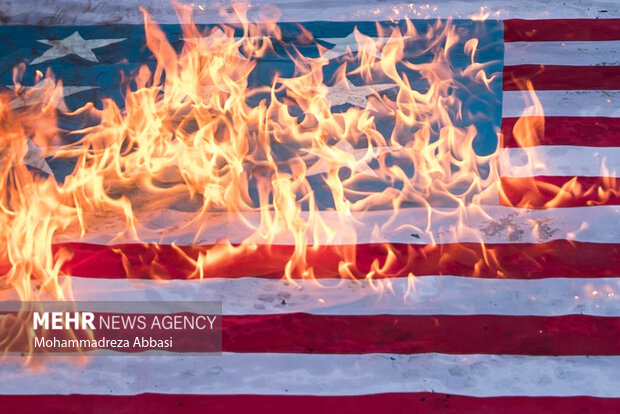 پرچم آمریکا در حال سوختن در مراسم یوم الله ۱۳ آبان در تهران در تصویر دیده می شود