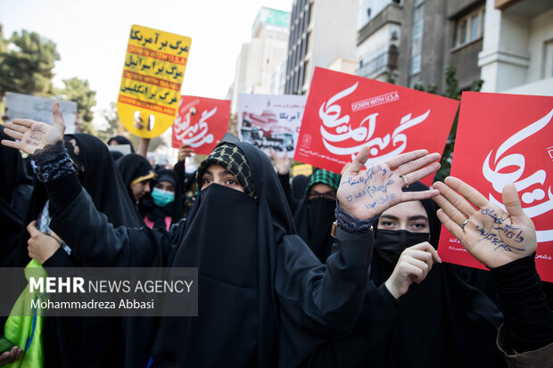 عده ای از شرکت کنندگان در مراسم یوم الله ۱۳ آبان در تهران شعار هایی بر روی دستان خود نوشته اند