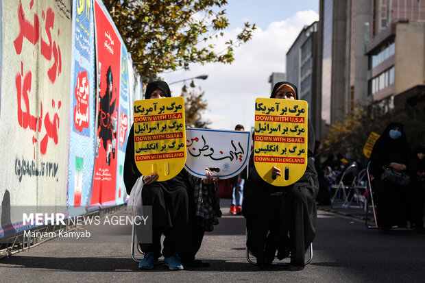 پلاکارد مرگ بر آمریکا در دست شرکت کنندگان در راهپیمایی 13 آبان در تهران می باشد