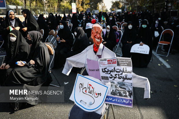 تصویر کاریکاتور جو بایدن در مراسم یوم الله ۱۳ آبان در تهران در مقابل لانه جاسوسی آمریکا در تصویر دیده می شود