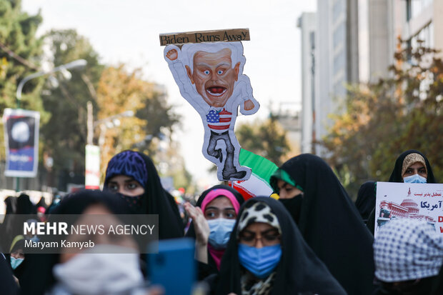 تصویر کاریکاتور جو بایدن در مراسم یوم الله ۱۳ آبان در تهران در مقابل لانه جاسوسی آمریکا در تصویر دیده می شود